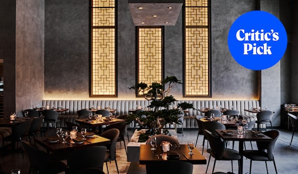 A modern dining room with tall, Asian-influenced decorative wall panels emitting warm light with a bonsai tree in the center of the room