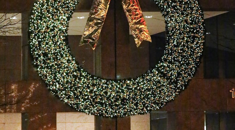 A pedestrian strolls by the giant Christmas wreath hanging above the front doors at Georgia Pacific in downtown Atlanta earlier this week. JOHN SPINK/JSPINK@AJC.COM
