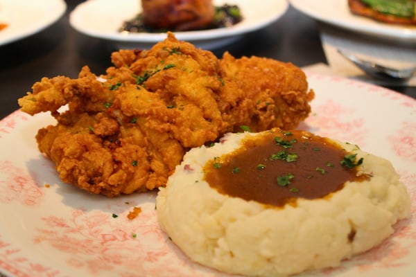 A piece of fried chicken with a side of mashed potatoes and gravy