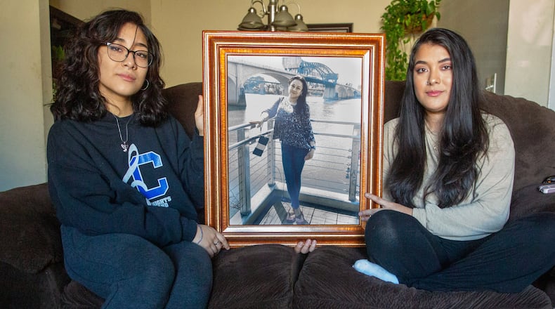 Jessica Aguilar, right, and her sister Jennifer sit by a photograph of their mother in their Roswell home on Sunday, January 23, 2022. (Steve Schaefer for The Atlanta Journal-Constitution)