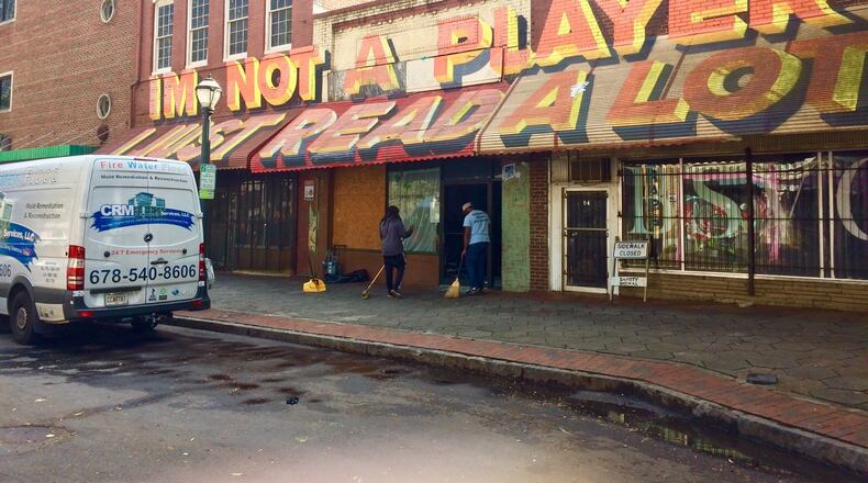 Cleanup crews get ready to board up windows at a building on Broad Street after an overnight shooting.