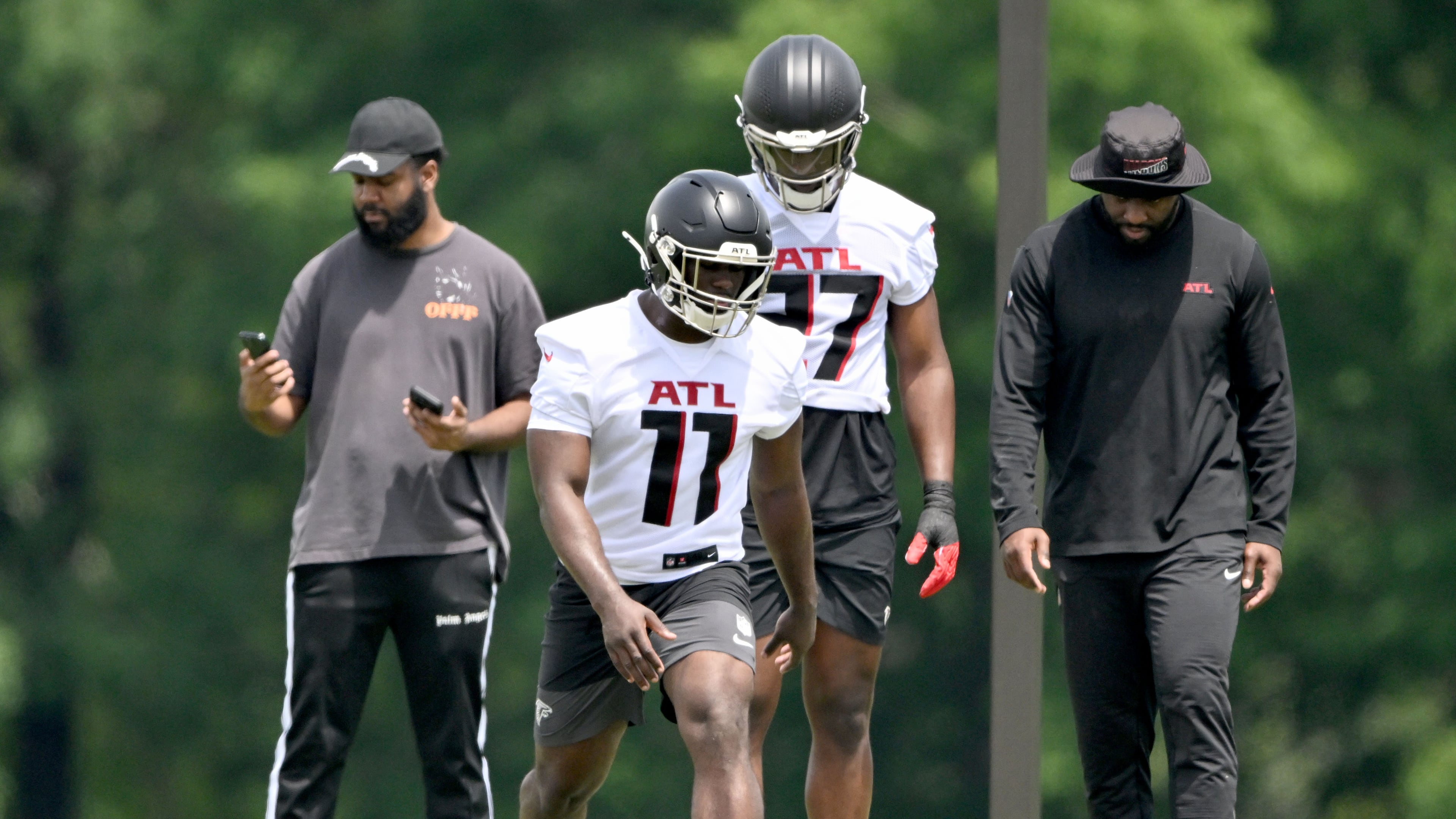 Atlanta Falcons rookie defenders Jalon Walker (center left) and James Pearce Jr. (center right), here running a drill during rookie minicamp in May, seem to be bringing a new, tougher mentality to the team this training camp. (Hyosub Shin/AJC)