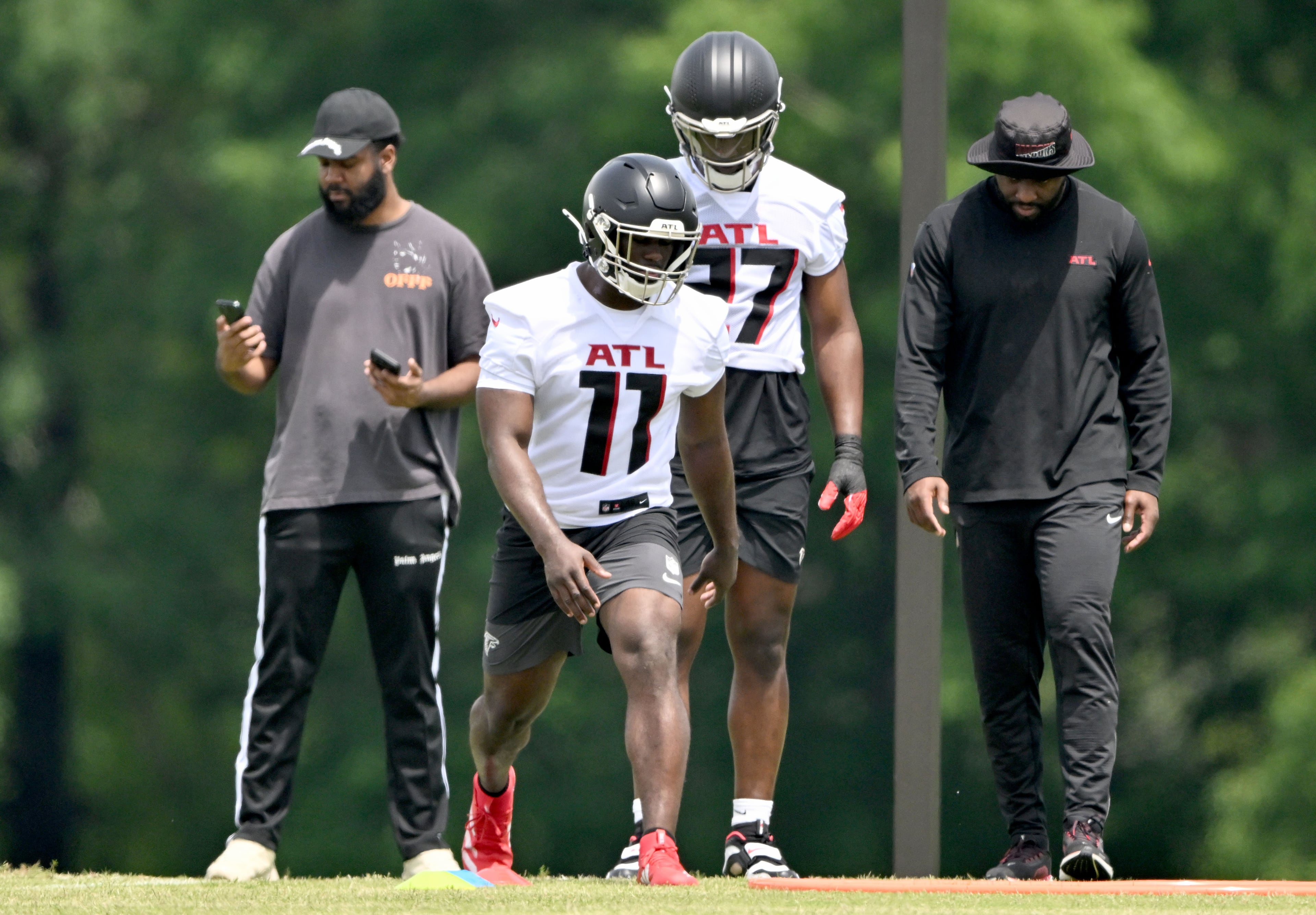 Atlanta Falcons rookie defenders Jalon Walker (center left) and James Pearce Jr. (center right), here running a drill during rookie minicamp in May, seem to be bringing a new, tougher mentality to the team this training camp. (Hyosub Shin/AJC)