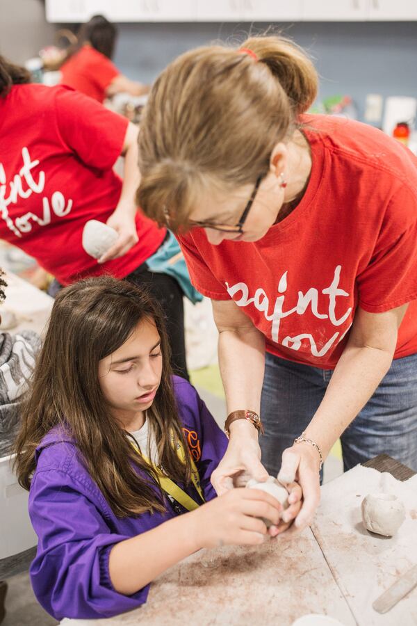 Ellen Gadberry helps a student at Kate’s Club create a clay animal mask to talk about how grief expresses itself.
