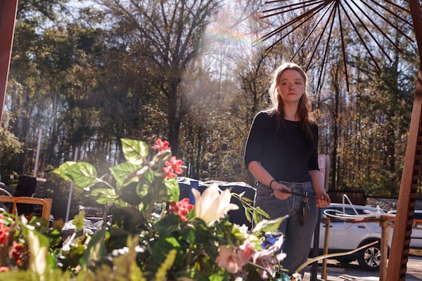 Hannah Hendricks stands in front of artificial flowers and other art supplies salvaged from her studio space after a fire burned a large portion of South River Arts Studio in DeKalb County on Friday, Nov. 14, 2025. (Natrice Miller/AJC)
