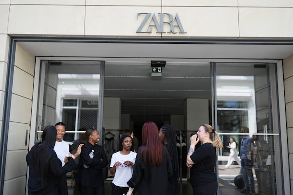 Employees stand outside a shop during an electricity outage in Cannes, southern France, Saturday, May 24, 2025. (AP Photo/Natacha Pisarenko)