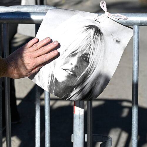 A woman touches a poster showing actor Brigitte Bardo near her home in Saint-Tropez, southern France, Sunday, Dec. 28, 2025 after the French 1960s sex symbol who became one of the greatest screen sirens of the 20th century and later a militant animal rights activist and far-right supporter, has died. She was 91. (AP Photo/Philippe Magoni)