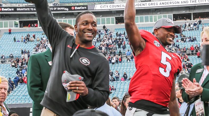 Georgia interim head coach Bryan McClendon, left, with game trophy and wide receiver Terry Godwin (5) with the MVP trophy, celebrated after defeating Penn State 24-17 in the TaxSlayer Bowl on Saturday, Jan. 2, 2016, in Jacksonville, Fla. Georgia won 24-17. (Gary Lloyd McCullough/The Florida Times-Union via AP)