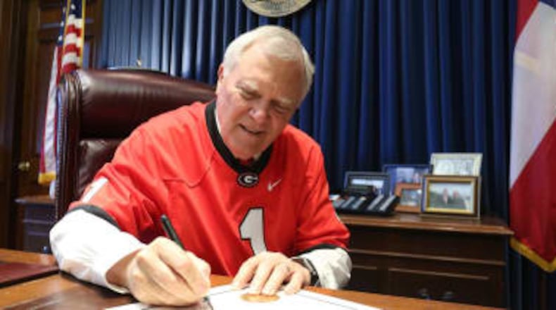Georgia Gov. Nathan Deal, wearing a Georgia Bulldogs football jersey, signs a proclamation supporting the team before its national championship game against the Alabama Crimson Tide in January 2018.