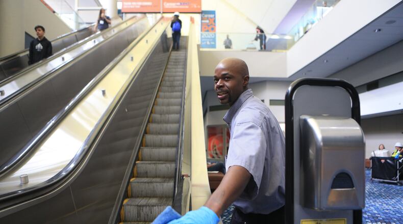 Dion Smith wipes down the escalator during the Construction Education Foundation of Georgia (CEFGA) career expo on Thursday, March 12, 2020, at the World Congress Center in Atlanta. This year, additional safety measures were implemented, including mandatory hard hats and wipe downs of surfaces people touch. CHRISTINA MATACOTTA, FOR THE ATLANTA JOURNAL-CONSTITUTION