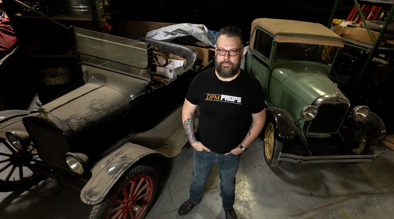 Thomas Kerns poses for a photo in front of a Ford Model T and a 1928 Ford Model A in his Atlanta prop house on July 25. Kerns' prop house employed five crew members, but he had to lay all of them off about three months ago. (Steve Schaefer/steve.schaefer@ajc.com)