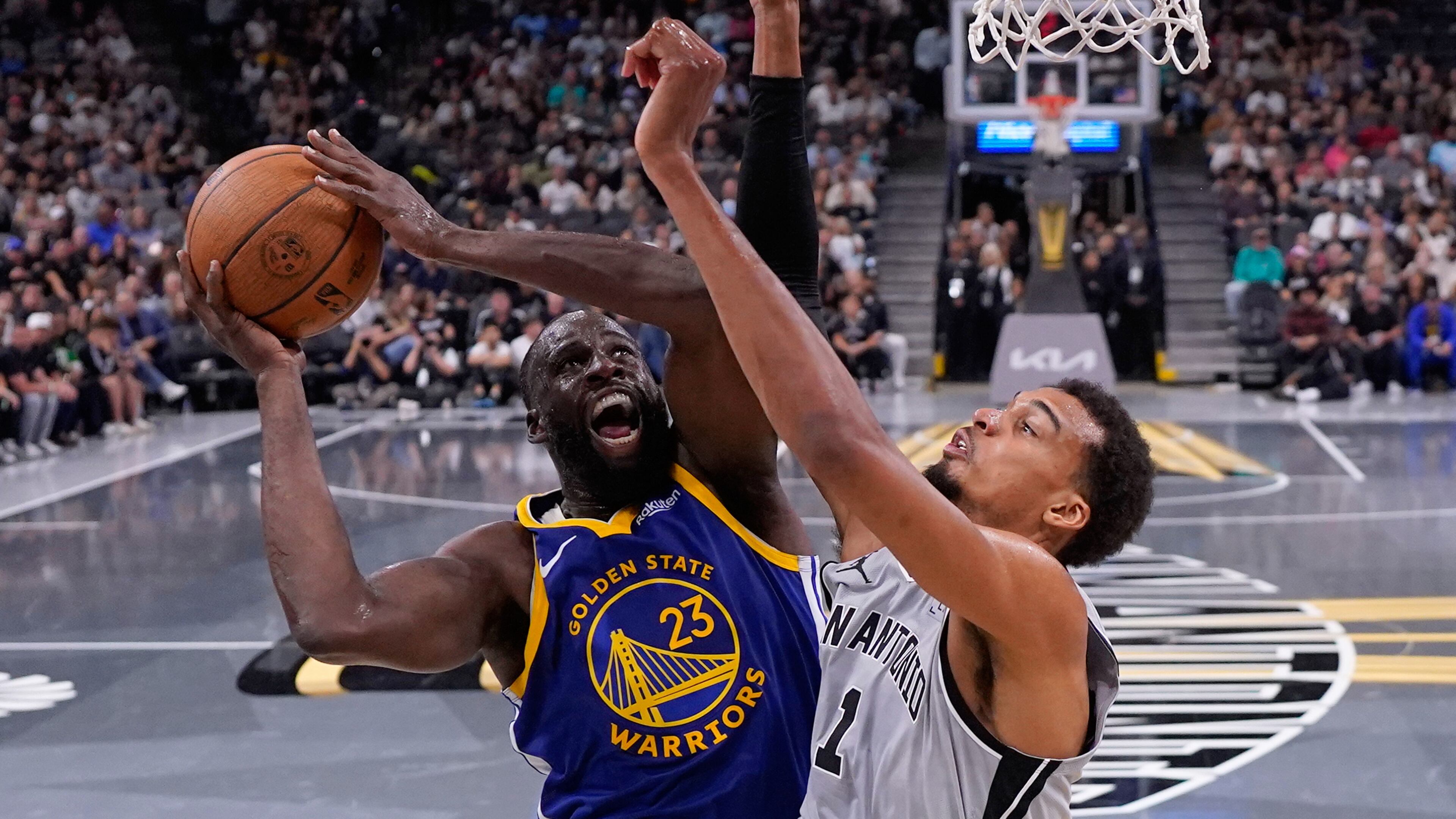 Golden State Warriors forward Draymond Green (23) drives to the basket against San Antonio Spurs forward Victor Wembanyama (1) during the second half of an NBA Cup basketball game in San Antonio, Friday, Nov. 14, 2025. (AP Photo/Eric Gay)