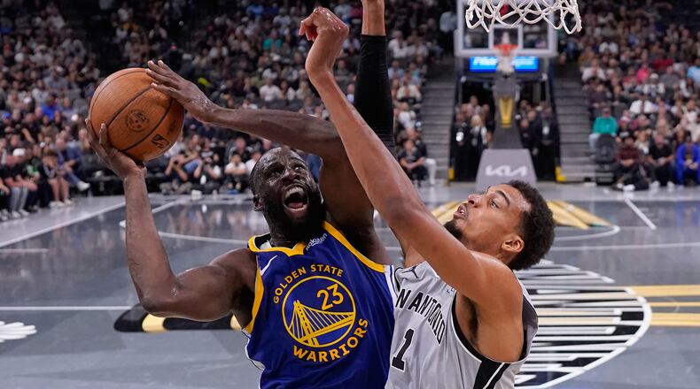 Golden State Warriors forward Draymond Green (23) drives to the basket against San Antonio Spurs forward Victor Wembanyama (1) during the second half of an NBA Cup basketball game in San Antonio, Friday, Nov. 14, 2025. (AP Photo/Eric Gay)