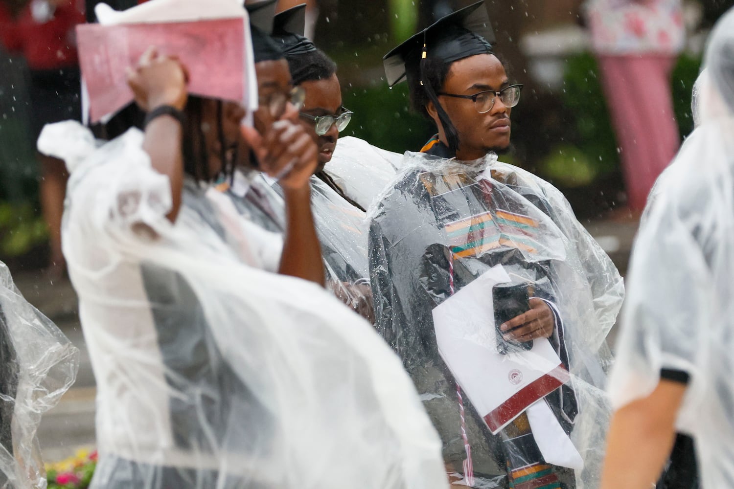 Graduates cover from the rain as they walk to the Martin Luther King International Chapel to continue the ceremony indoors at Morehouse College’s 141st  Commencement Ceremony on Sunday, May 18, 2025.
(Miguel Martinez/ AJC)