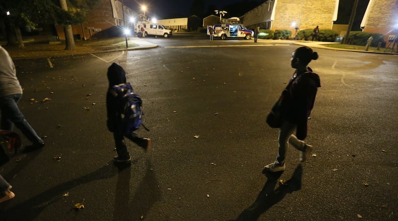 Leon Adam Hunter and Aaliyah March walk through an area where one man was killed and two others wounded Wednesday in an early morning shooting at a DeKalb County apartment complex. The children, whose mother is Linette March, were on their way to a bus stop.