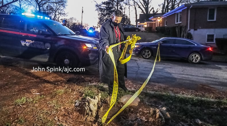 A homicide detective removes crime scene tape on Center Hill Avenue, where the body of a shooting victim was found inside a car that crashed and burned.