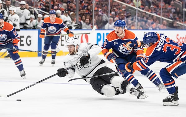Los Angeles Kings' Alex Laferriere (14) falls while being pressured by Edmonton Oilers' Mattias Janmark (13) and Viktor Arvidsson (33) during the first period of Game 4 in an NHL hockey first-round playoff series in Edmonton, Alberta, Sunday, April 27, 2025. (Jason Franson/The Canadian Press via AP)