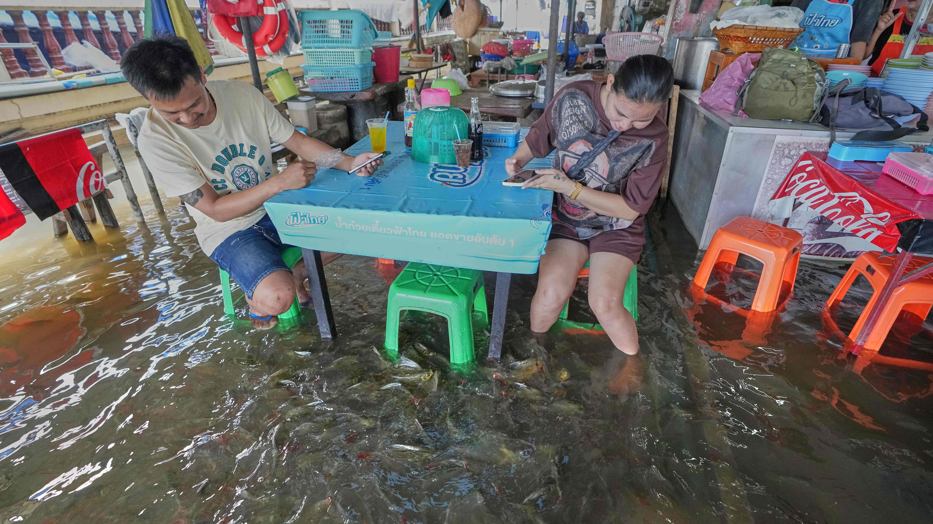 Diners at the Pa Jit restaurant watch fish swim in the aisles due to flooding from the Tha Chin River in Thailand's Nakhon Pathom Province west of Bangkok, Thailand, Friday, Nov. 14, 2025. (AP Photo/Sakchai Lalit)