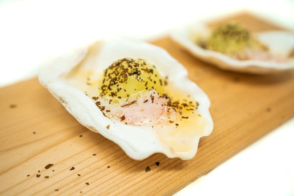 Cured honeydew in the shape of an oyster on the half shell topped with a creamy sauce and seasoning.