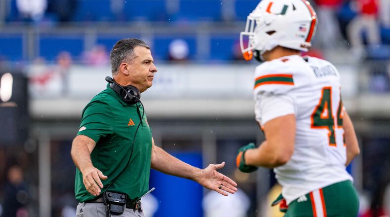Miami head coach Mario Cristobal greets players as they come off the field during the first half of an NCAA college football game against SMU, Saturday, Nov. 1, 2025, in Dallas. (AP Photo/Jeffrey McWhorter)