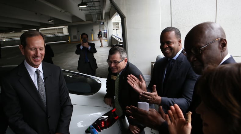 Officials ceremonially plug a Tesla into an electric vehicle charger at Hartsfield-Jackson's international terminal. Credit: Henry Taylor