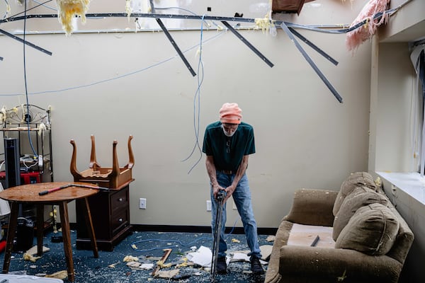Mike Davis moves debris from a damaged business in the Triad Building, a business plaza, after severe weather passed through Thursday, April 3, 2025, in Louisville, Ky. (AP Photo/Jon Cherry)