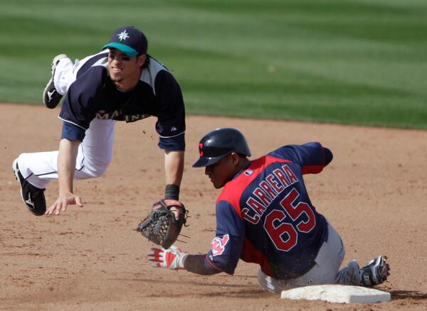 Seattle Mariners second baseman Sean Kazmar hurdles Cleveland Indians' Ezequiel Carrera while relaying to first to complete a double play in the fifth inning of a spring training baseball game in Peoria, Ariz., Saturday, March 5, 2011. (AP Photo/Lenny Ignelzi)