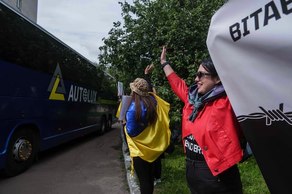 Olha Kurtmalaieva waves to Ukrainian marine soldiers sitting in a bus after a POWs exchange between Russia and Ukraine, in Chernyhiv region, Ukraine, Saturday, June 14, 2025. (AP Photo/Evgeniy Maloletka)