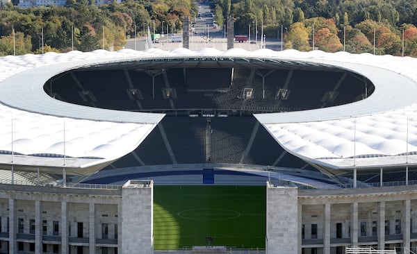 FILE - In this Friday, Oct. 5, 2018 photo people walk down the stairs in the stands of the Olympic Stadium in Berlin, Germany. (AP Photo/Michael Sohn, file)