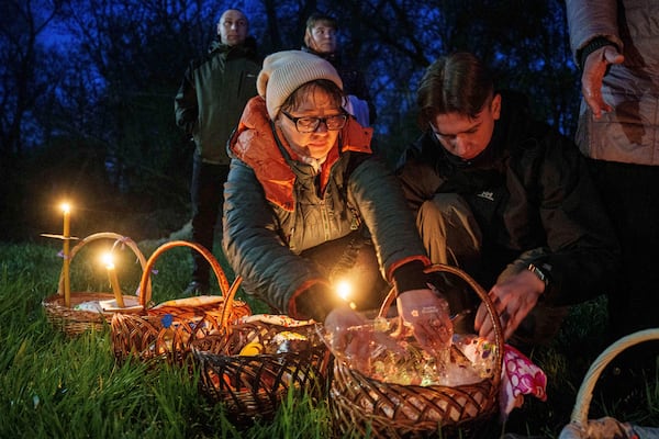 People prepare their Easter baskets to be blessed in front of a church destroyed in fighting between Russian and Ukrainian forces, during celebration of the Orthodox Easter in Lukashivka village, Ukraine, on Sunday, April 20, 2025. (AP Photo/Evgeniy Maloletka)