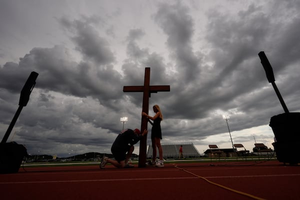 Dan Beazley, of Michigan, left, reacts as he holds a large cross with Abigail Smithson during a vigil for flooding victims at Tivy Antler Stadium on Wednesday, July 9, 2025, in Kerrville, Texas. (AP Photo/Gerald Herbert)
