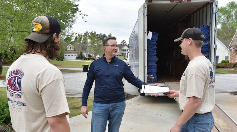Chris New (center), owner of Barnes Van Lines, hands over paperwork to Anson Strickland as Joe Nowak (left) looks on while moving a family in Villa Rica on Thursday, April 15, 2021. (Hyosub Shin / Hyosub.Shin@ajc.com)