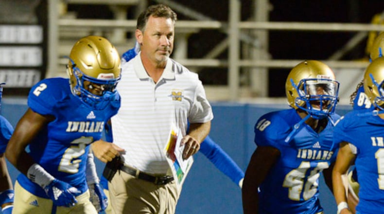 McEachern head coach Kyle Hockman (center) takes the field along with the Indians prior to the start of their game against Cedar Grove Friday, Sept. 7, 2018, at McEachern High School in Powder Springs.