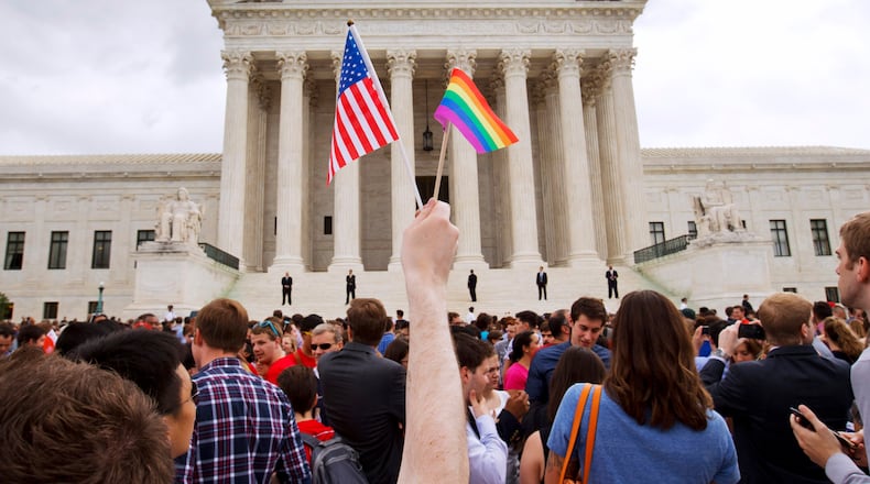 In this June 26, 2015 file photo, a man holds a U.S. and a rainbow flag outside the Supreme Court in Washington after the court legalized gay marriage nationwide. (AP Photo/Jacquelyn Martin)