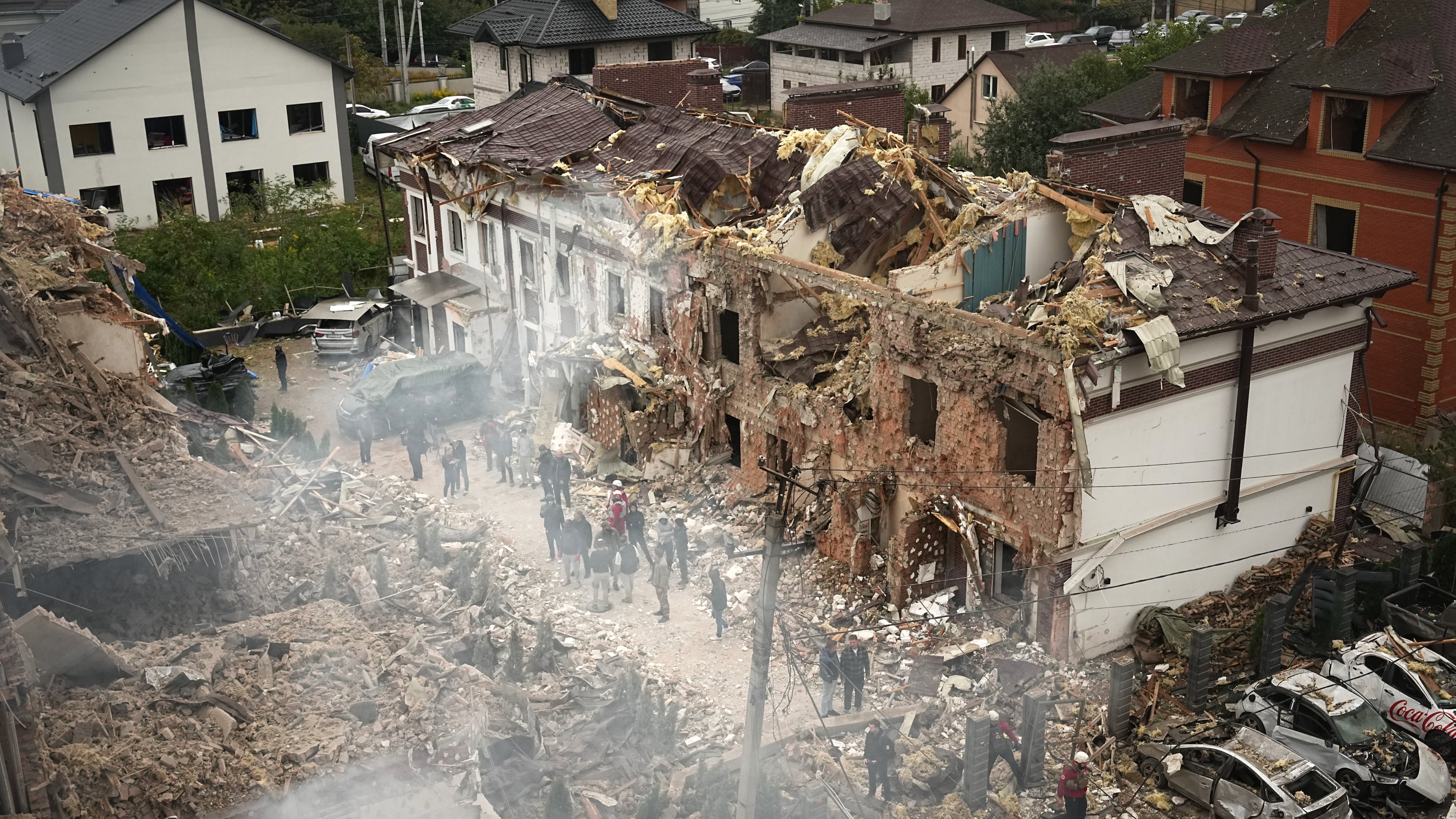 People seen at the site of an apartment building destroyed during a Russian attack in Kyiv, Ukraine, Sunday, Sept. 28, 2025. (AP Photo/Efrem Lukatsky)