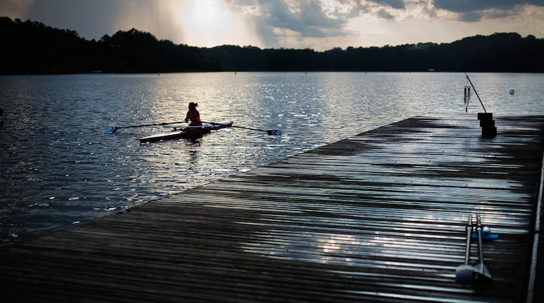 In this July 19, 2016, photo, a rower moves past the launching docks at Lake Lanier Olympic Park, home of the 1996 Summer Olympic Games rowing events, in Gainesville, Ga. This man-made lake still has its rowing facilities, which have been used for major competitions over the last two decades. This year, it hosted an Olympic qualifier for Rio and will host the Dragon Boat World Championships in 2018. (AP Photo/David Goldman)