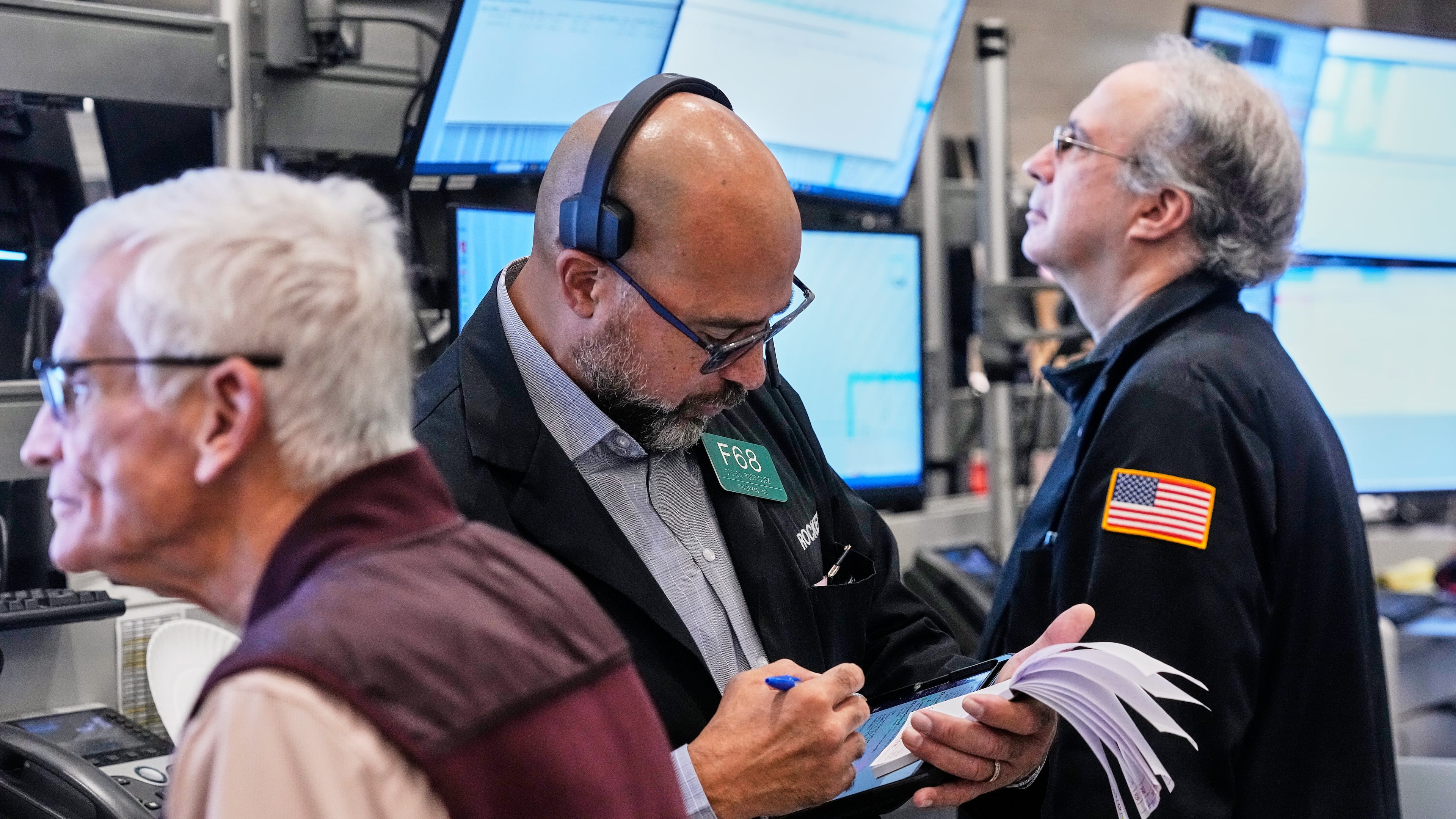 Options trader Steven Rodriguez, center, works on the floor of the New York Stock Exchange, Monday, Oct. 20, 2025. (AP Photo/Richard Drew)