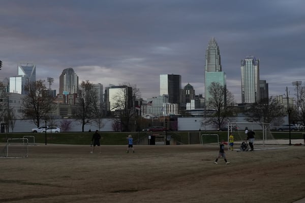 Children walk through a sports field in Independence Park under the skyline of Charlotte, N.C., on March 20, 2025. (AP Photo/Mary Conlon)
