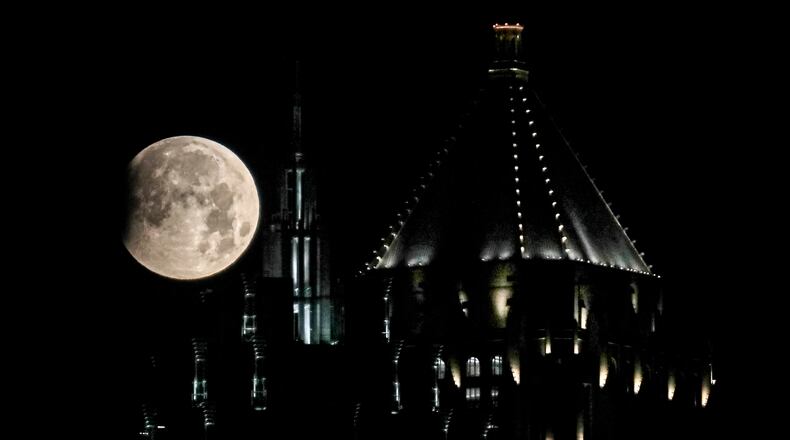 A super moon hovered over Promenade II (left) and One Atlantic Center (right) in midtown Atlanta on Wednesday, May 26, 2021, as the beginning of the first total lunar eclipse since January 2019 appeared Wednesday over North Georgia. The lunar eclipse became visible in the sky about 5:44 a.m. and peaked at 6:34 a.m., just before sunrise. (John Spink / John.Spink@ajc.com)