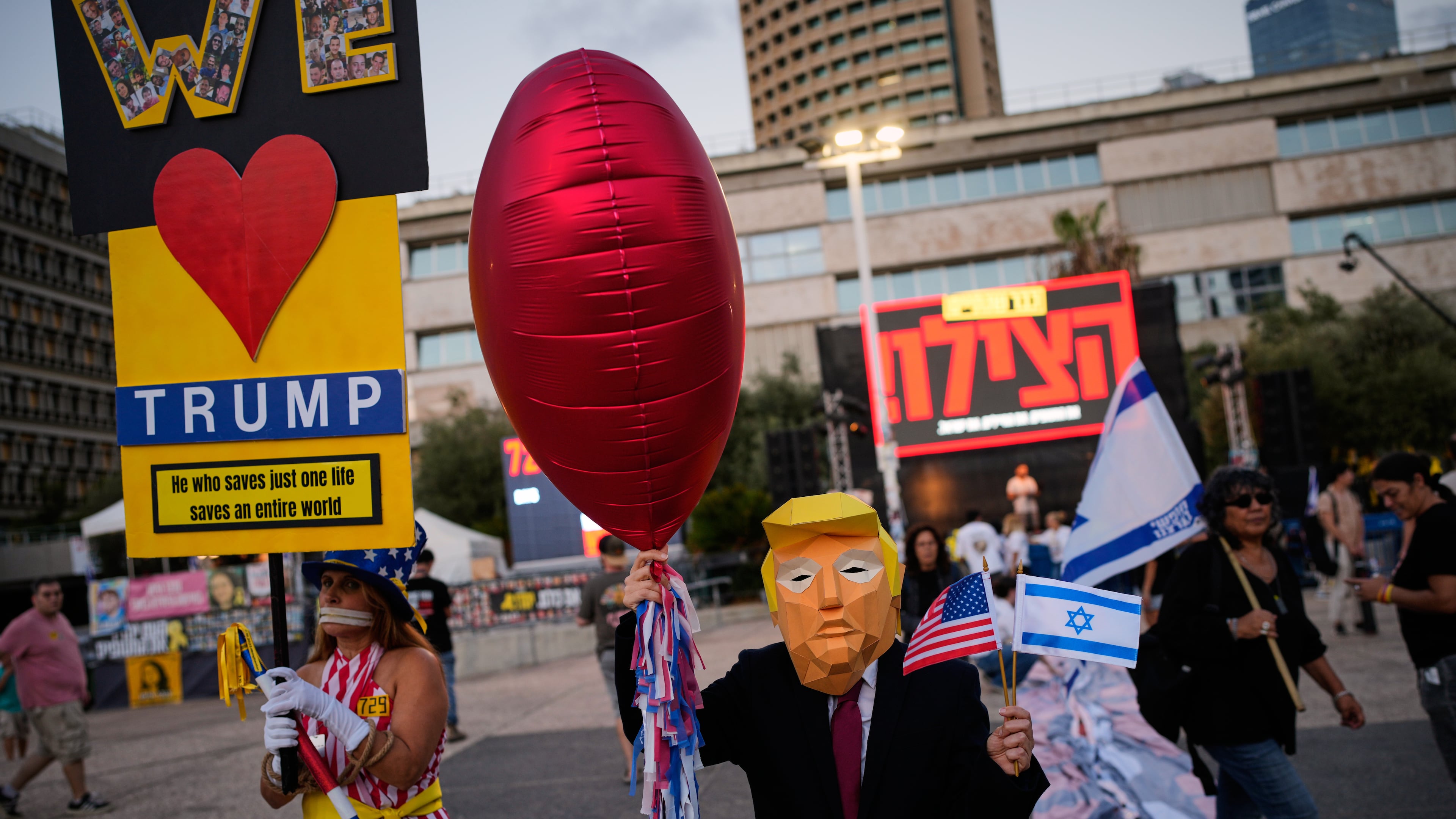 A woman wearing a mask depicting U.S. president Donald Trump attends a rally calling for the release of all hostages held in the Gaza Strip and urges a ceasefire, in Tel Aviv, Israel, Saturday, Oct. 4, 2025. ahead of the second anniversary of the Israel-Hamas war. (AP Photo/Ohad Zwigenberg)
