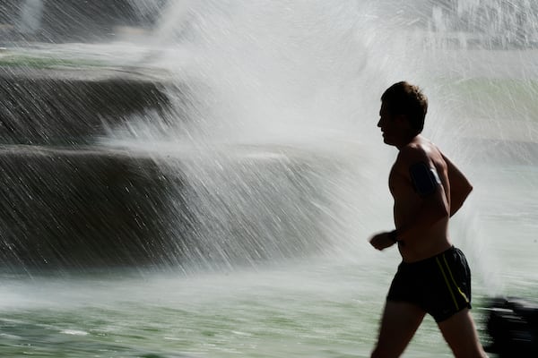 A man runs past a fountain as temperatures approach 100 degrees, Friday, June 20, 2025, in Kansas City, Mo. (AP Photo/Charlie Riedel)