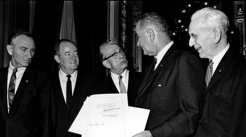 FILE - President Lyndon B. Johnson holds the signed document of the Voting Rights Act of 1965 as he chats with Sen. Everett Dirksen, R-Ill., in the President's Room in Washington, Aug. 6, 1965. Signatures that appear on the document are Johnson, left bottom; House Speaker John McCormack, upper, standing at right; and Vice President Hubert Humphrey, lower, standing second from left. Standing at far left is Sen. Mike Mansfield. (AP Photo)