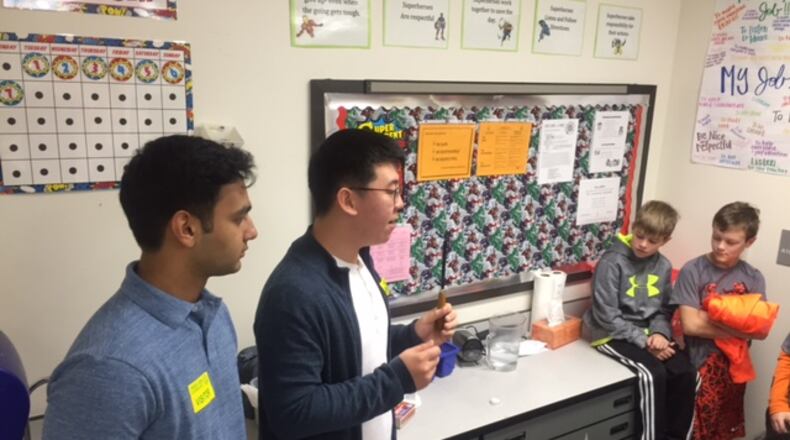 Alpharetta High School students teach a science lesson to Creek View students Matthew Kloecker and Wesley Austin, from Adrienne Hunter’s fourth-grade class.