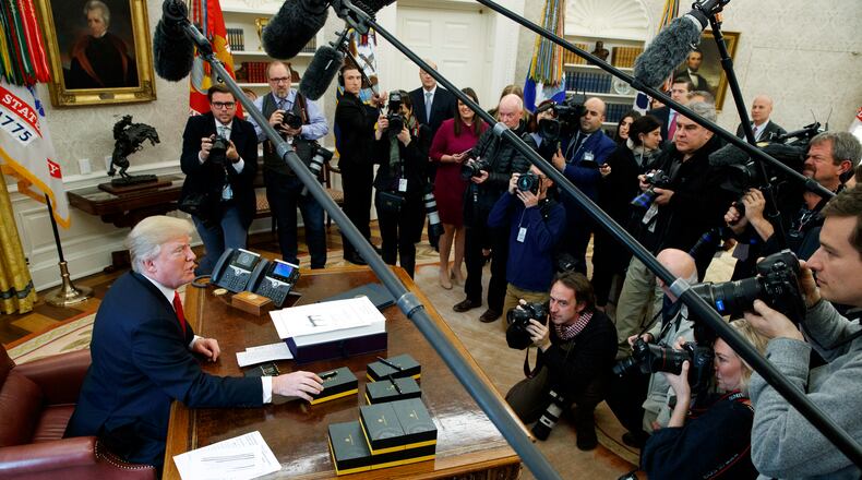 President Donald Trump offers pens to reporters after signing the tax bill and continuing resolution to fund the government, in the Oval Office of the White House on Friday. AP/Evan Vucci