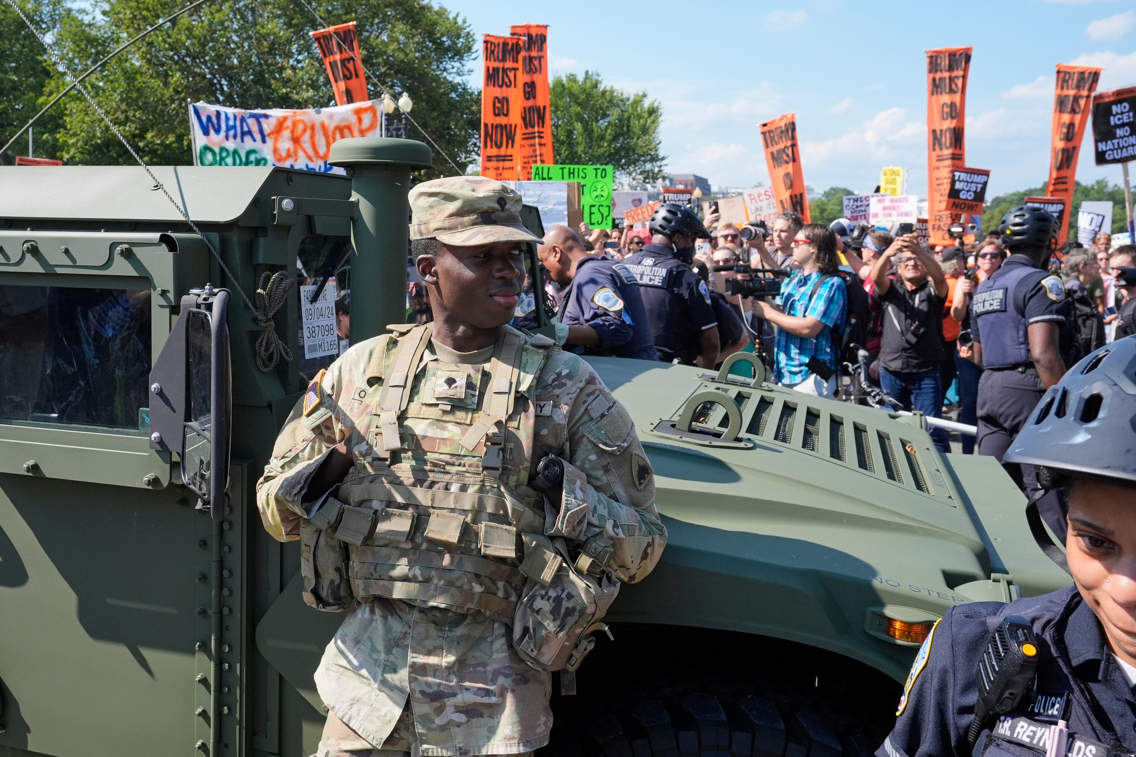 Washington Metropolitan Police officers and military police soldiers with the District of Columbia National Guard kept watch Saturday as activists protested the federal takeover of policing there.