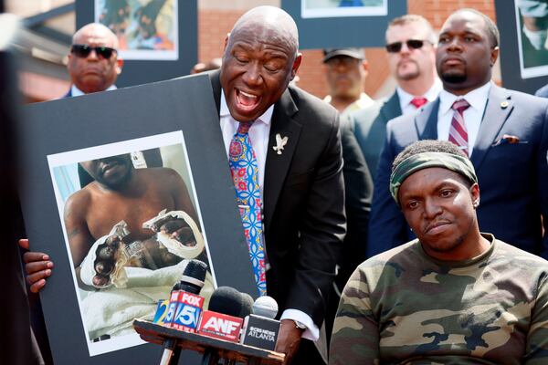 Civil rights attorney Ben Crump, left, his legal team and other supporters of Rashaad Muhammad, seated right, address the press outside the Fulton County Jail, Wednesday, April 29, 2026, in Atlanta, as he calls for a criminal investigation into alleged medical neglect of Muhammad. (Miguel Martinez/AJC)