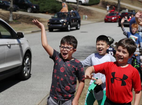 Will Springfield (left), 8, reacts with joy to seeing his second grade teacher Ms. Chriss pass by as teachers from Roberts Elementary hold a school parade, driving through area neighborhoods for some face-to-face contact while still maintaining social distance to ease the separation anxiety of their students during the coronavirus on Wednesday, March 25, 2020, in Suwanee. Although distance learning is allowing kids to connect with teachers and get lessons done, the personal touch is missing. CURTIS COMPTON CCOMPTON@AJC.COM