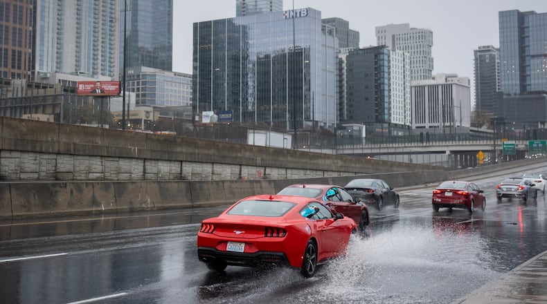 Vehicles drive through a flooded section of Techwood Drive in downtown Atlanta on Tuesday, Nov. 25, 2025. A cold front is pushing the storms across the state. (Ben Hendren for the AJC)