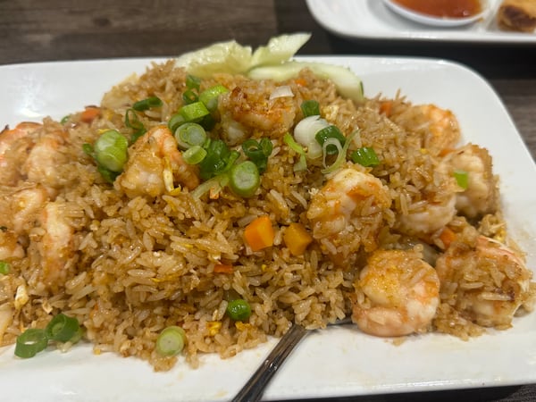 A large square plate is filled with fried rice studded with shrimp and topped with green onions