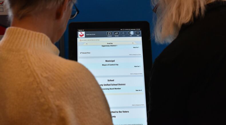 Event participants check out Dominion Voting Systems’ electronic voting system last January. HYOSUB SHIN / HSHIN@AJC.COM